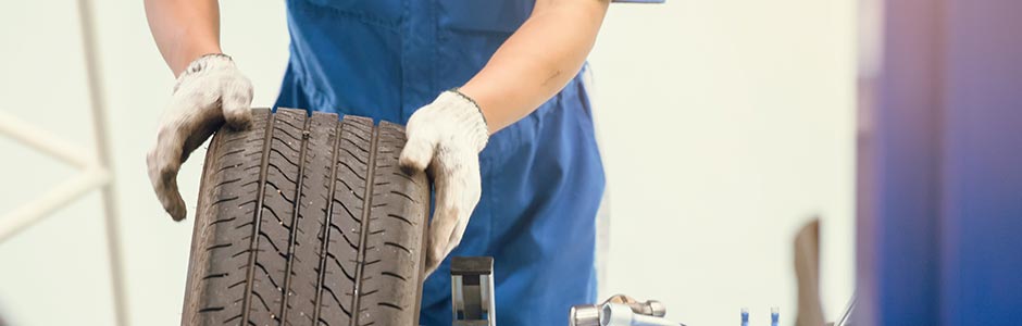 mechanic rolling tyre inside the garage