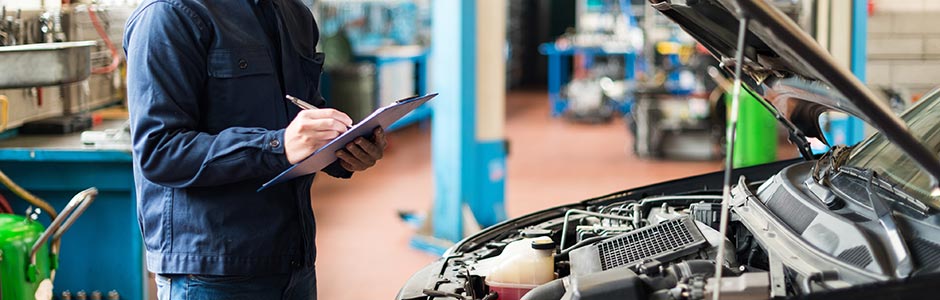 Mechanic carrying out MOT test, checking under the bonnet of a car