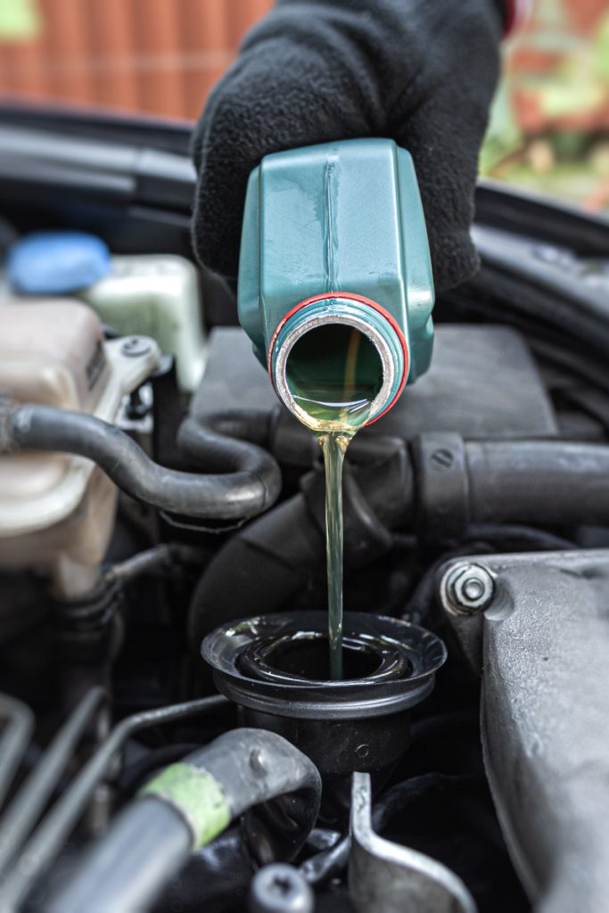 Mechanic pouring engine oil into a vehicle - Vehicle Servicing Plymouth